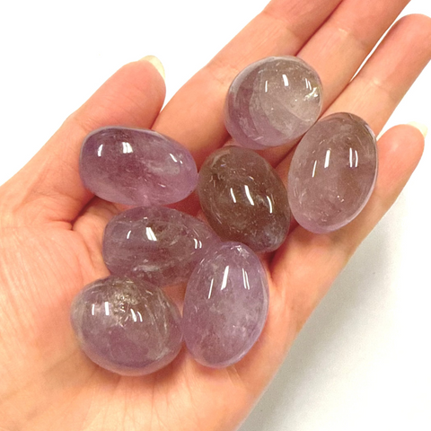 Hand holding purple amethyst gemstones against a white background