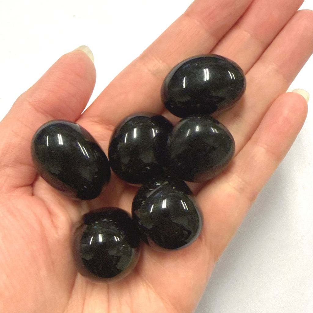 Hand holding  black obsidian crystal stones against a white background