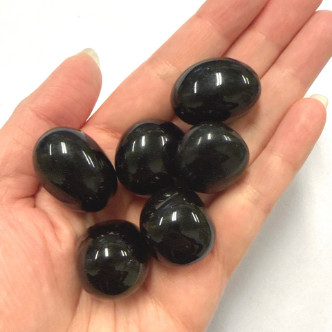 Hand holding  black obsidian crystal stones against a white background