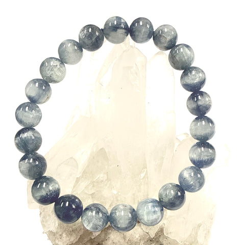 Blue Kyanite Bracelet 8mm bead size showing on a clear quartz cluster with white background