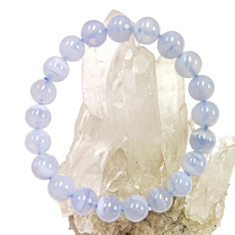 A bracelet made of blue lace agate beads with elastic stretching cord, displayed in front of a crystal.
