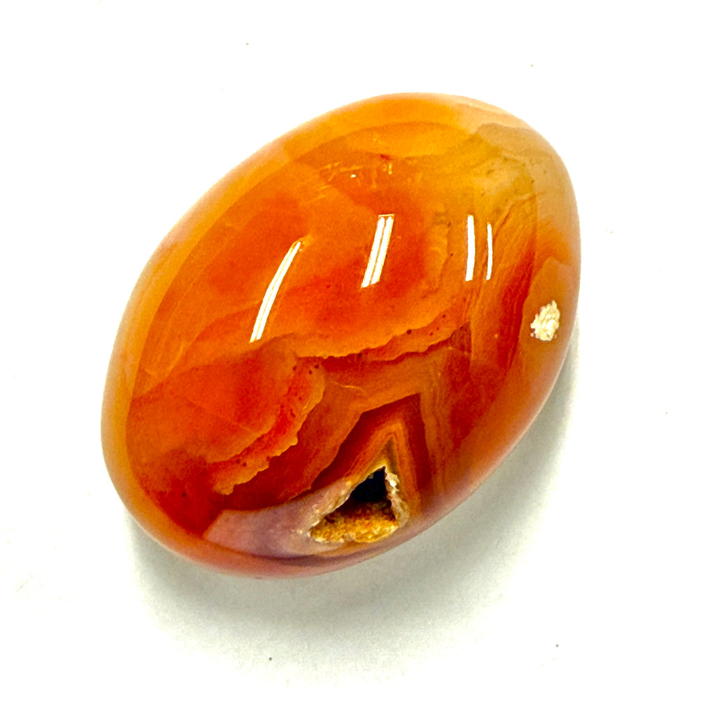 Carnelian Orange read agate stone with a geodo on the surface  on a white background