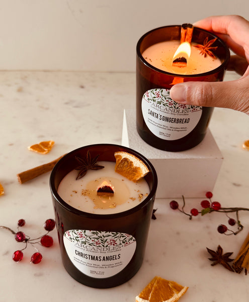 Two candles labeled 'Christmas Angels' and Gingerbread on a marble surface with decorative elements.