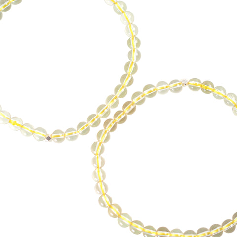 A bracelet made of yellow citrine stones, laid out on a white surface.