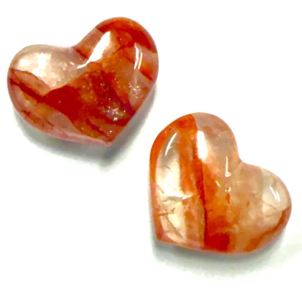 Two heart-shaped Fire Quartz stones with orange and white marbled pattern on a white background