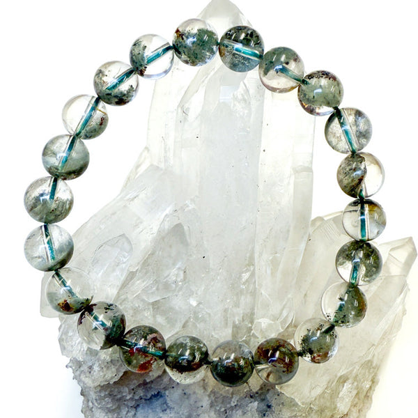 Beaded bracelet with green phantom quartz stones on a crystal background