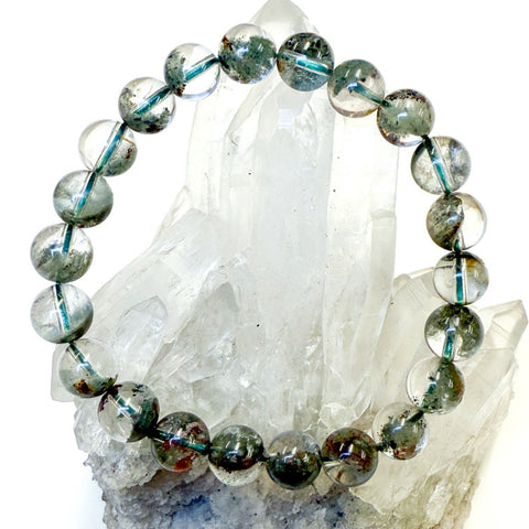 Beaded bracelet with green phantom quartz stones on a crystal background