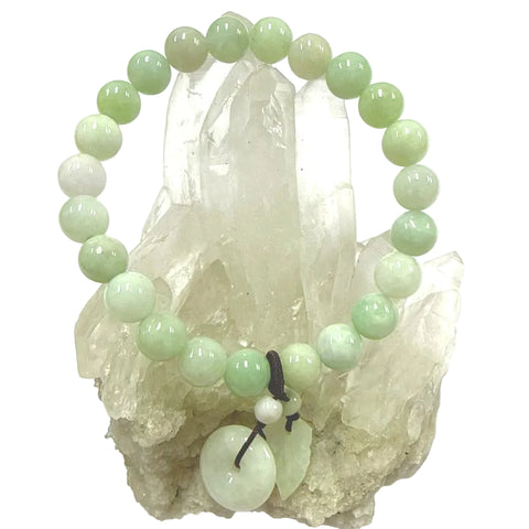Green jade beaded bracelet with a leaf and donut charm on a crystal background