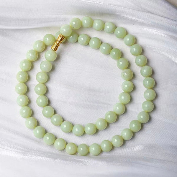 Light green beaded necklace with a gold clasp on a white background