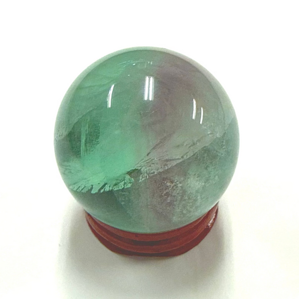 Green rainbow fluorite with a bit of purple crystal ball on a white background