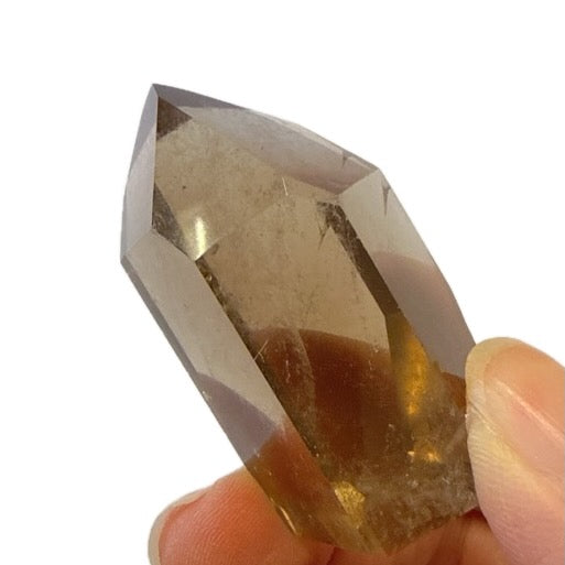 Smoky quartz crystal held in hand against a white background