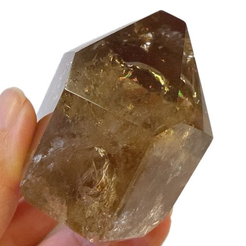 Hand holding a smoky quartz crystal against a white background