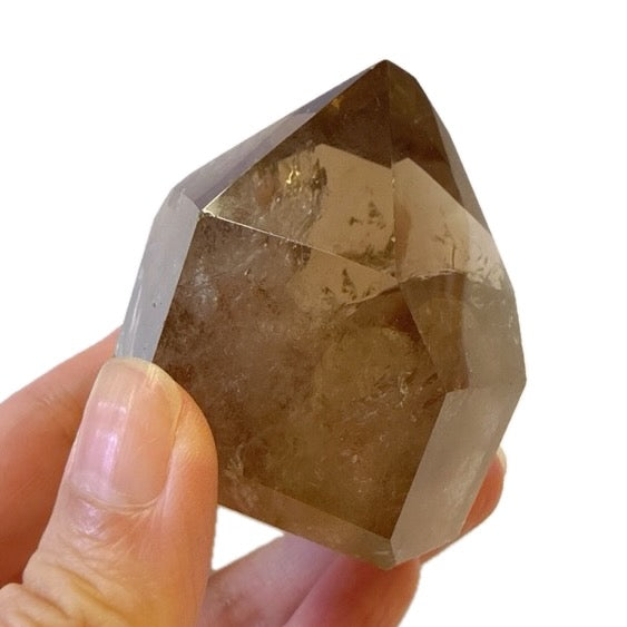 Smoky quartz crystal held in a hand against a white background