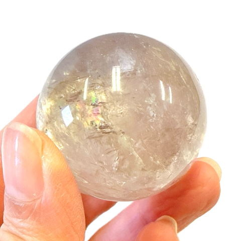 Smoky Quartz crystal ball held in a hand against a white background