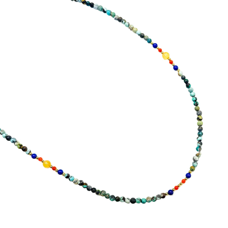 A beaded necklace with turquoise, lapis lazuli, red agate, and amber stones, strung together with a white background.