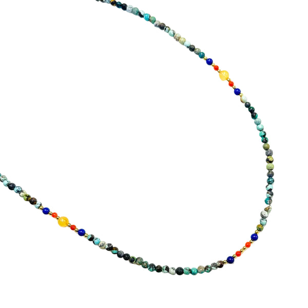 A beaded necklace with turquoise, lapis lazuli, red agate, and amber stones, strung together with a white background.