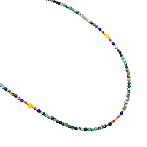 A beaded necklace with turquoise, lapis lazuli, red agate, and amber stones, strung together with a white background.