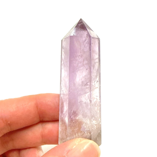 Hand holding an amethyst crystal with a white background