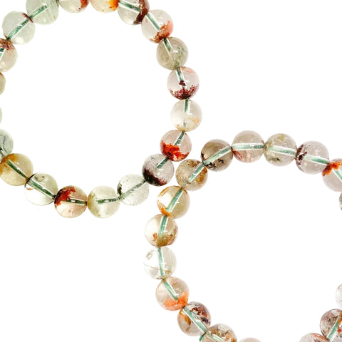 A multicolored garden phantom quartz beaded bracelet with a variety of colors, including clear, brown, and orange, featuring a elastic stretching cord.