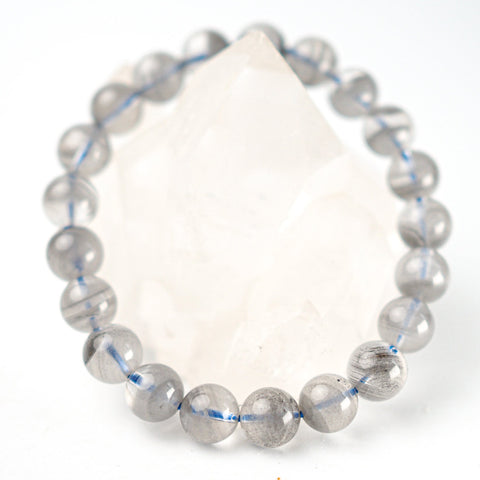 A bracelet made of grey tinted quartz beads with a striped pattern and a large clear quartz bead in the center, with an elastic stretching cord.