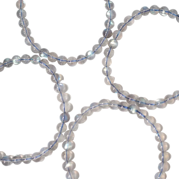A series of round labradorite beads with blue and white light reflections, strung on an elastic cord.